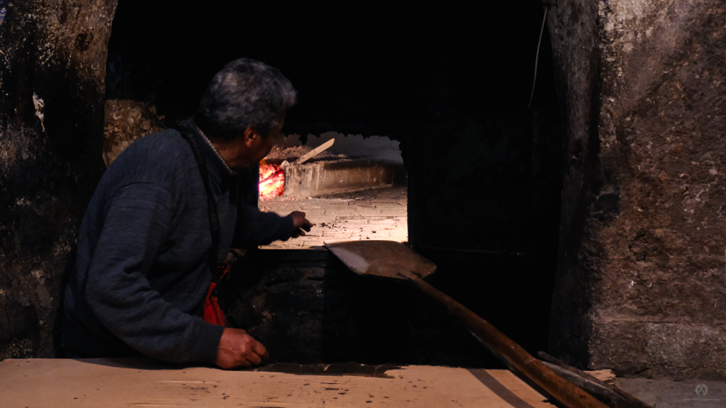 Baker in a traditional shared oven where everyone brings their own dough to be baked